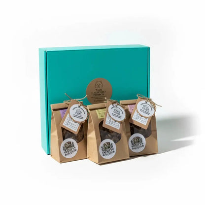 Pack Cachorro Pompón con caja turquesa cerrada y 5 bolsitas de snacks naturales con etiquetas colgantes redondas de Woof Natural dispuestas al frente, presentación completa del producto